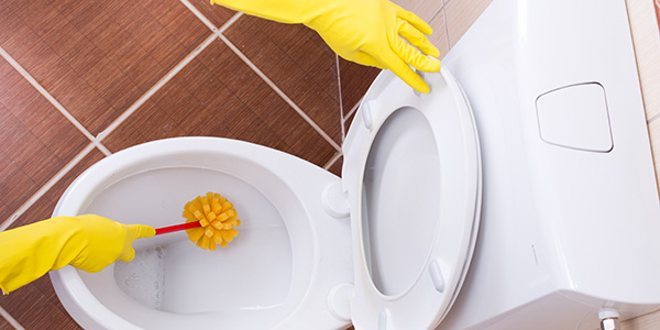 Gloved hands cleaning a public toilet